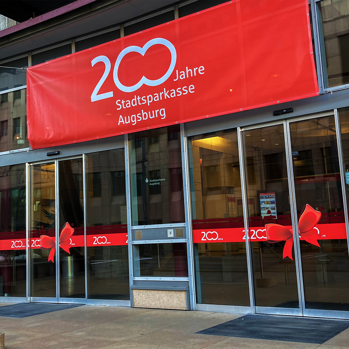Das 200-Jahre-Logo der Stadtspaarkasse Augsburg auf einem roten Banner über dem Haupteingang der Stadtspaarkasse Augsburg