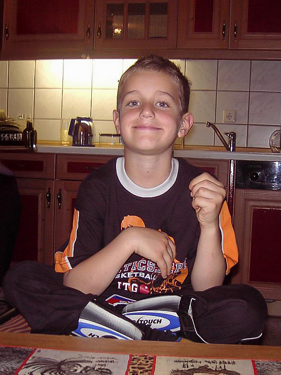 Ein Kinderfoto von Fabio Swigart. Er trägt Schienbeinschoner vom Fußball und ein oranges T-shirt.